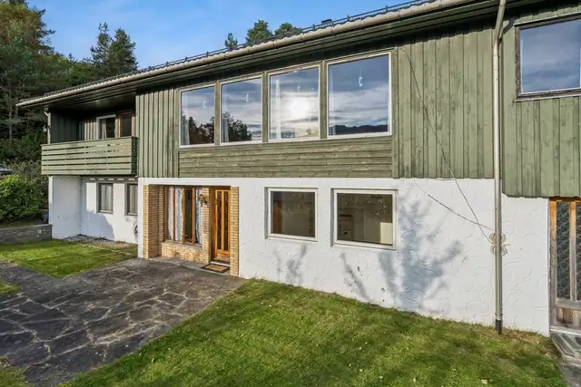 På hagesiden ligger en hellelagt uteplass inntil boligen, med dør ut fra underetasjen.